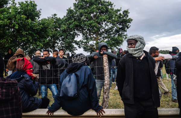 Migrants in Calais waited for a chance to run past the police to climb onto trains Thursday near the Channel Tunnel. Credit Tom Jamieson for The New York Times