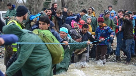 Refugees cross a river near Idomeni to enter Macedonia
